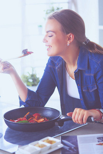 烹饪健康食品保温锅与蔬菜的年轻女子是它。健康的生活方式，在家里做饭的概念
