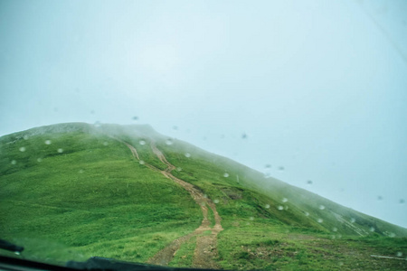 乌克兰夏季绿色的山脉。天空越过群山。乘吉普车旅行时的大气景观。越野远征。车内雨