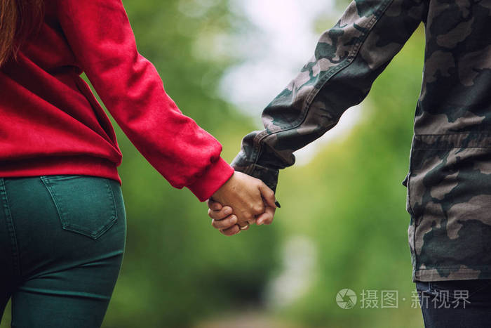 年轻的成人美丽的情侣在爱的男人和女人走在一起自然在公园手特写