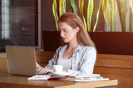 年轻女性自由职业者与笔记本电脑在咖啡馆工作