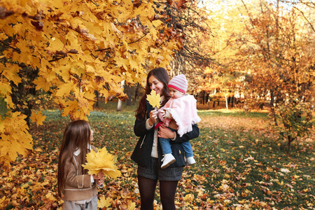 快乐的家庭在秋天散步。母女漫步在公园里, 享受着美丽的秋天自然