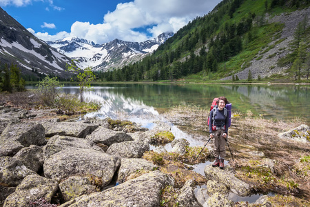 女人在湖在阿尔泰山的小路上徒步旅行