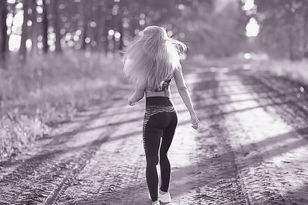 在夏日森林里奔跑的迷人女人。年轻运动妇女户外慢跑