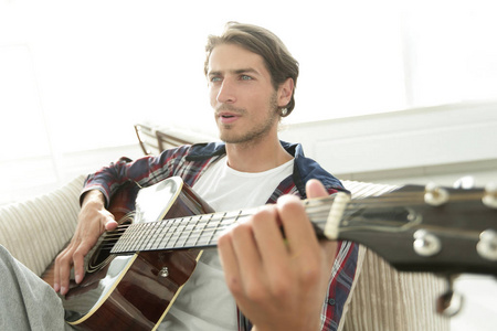 吉他坐在客厅沙发上的家伙。一种生活方式的概念