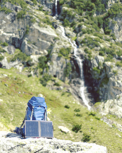 背包矗立在群山背景的小径上。太阳面板挂在背包上