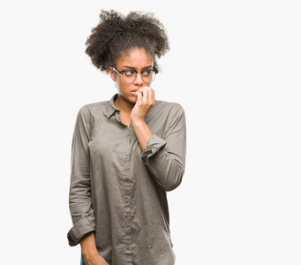 年轻的美国黑人妇女戴着眼镜在孤立的背景下, 看着压力和紧张的嘴咬指甲的手。焦虑问题