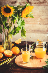 一杯鲜榨的橙汁和橘子在木桌上。秋天舒适质朴的心境静物