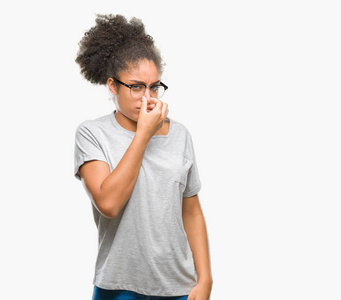 年轻的美国黑人妇女戴着眼镜在孤立的背景下闻到的东西发臭和恶心, 难以忍受的气味, 用手指在鼻子上呼吸。坏气味概念