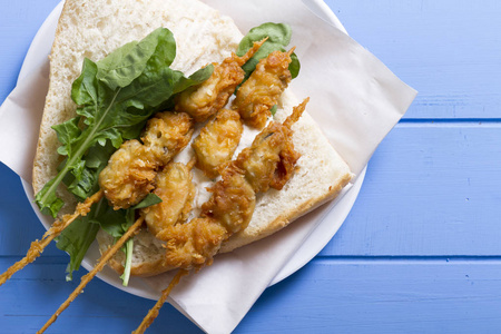 美味的金色深炸贻贝肉串三明治, 配酸奶酱, 番茄, 洋葱切片, 欧芹和