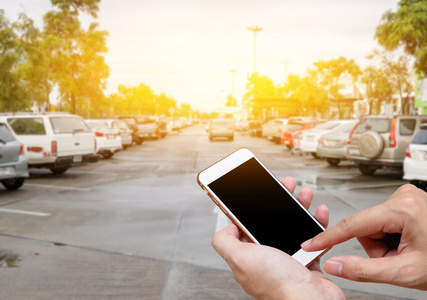智能手机在人的手上显示空白屏幕模糊汽车停车