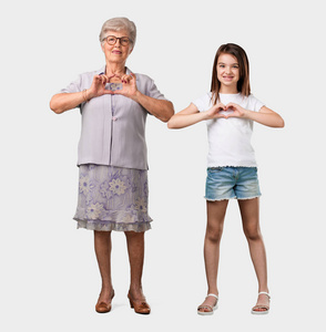 满身的老太太和她的孙女用手做心脏, 表达爱和友谊的概念, 快乐和微笑