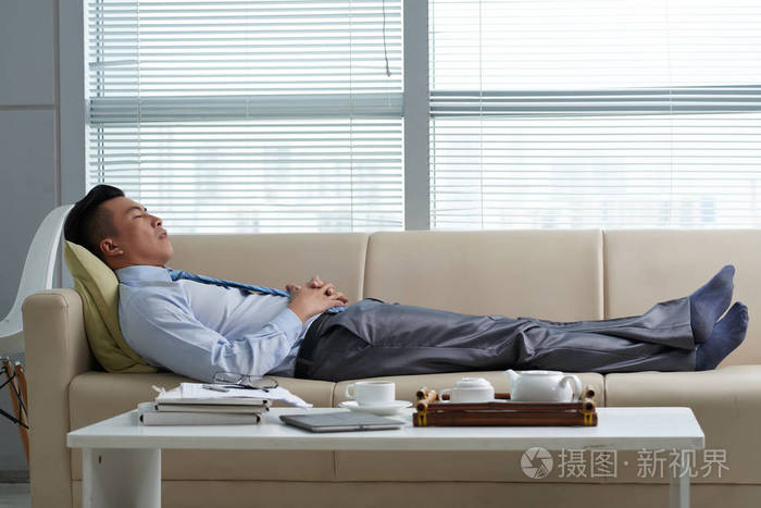 疲惫的越南商人在办公室沙发上睡觉