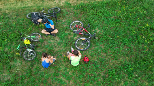 自行车家庭自行车户外空中无人机视图从上面, 快乐的积极的父母与孩子有乐趣和放松在草, 家庭体育和健身在周末