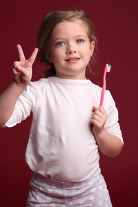 带牙刷的小女孩露出两个手指。 快关门。 红色