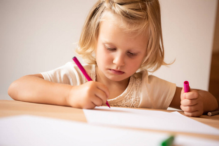 严重可爱的孩子画粉红色毡笔在幼儿园