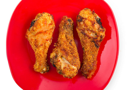 香脆烤鸡腿隔离在红瓷盘上, 特写, 顶部视图