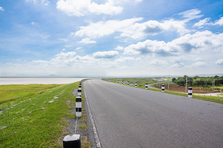 风景秀丽的公路在空旷的公路上行驶, 附近有一座有着天空和云层背景的大水库。Sak Jolasid 大坝泰国