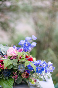在老式金属花瓶中拉长的插花。表设置。蓝色和红色的颜色。华丽的花束, 不同的花朵。背景公园