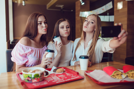 三个年轻女孩正在做快餐餐厅的自拍照
