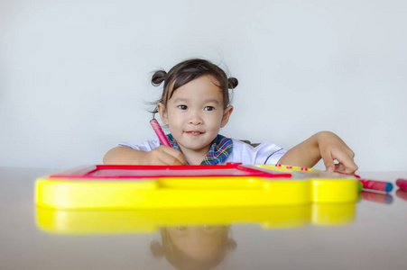 快乐可爱的亚洲小朋友坐在桌边玩五颜六色的玩具