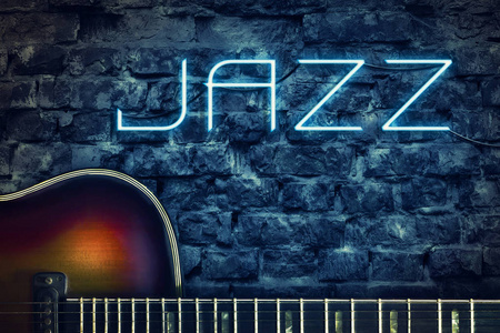 老式的吉他和霓虹灯铭文爵士乐在旧砖墙的背景。概念音乐