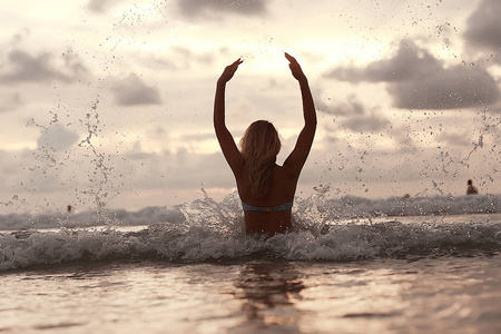 快乐的年轻女子在海滩上玩, 自由的概念和暑假的乐趣和跳跃
