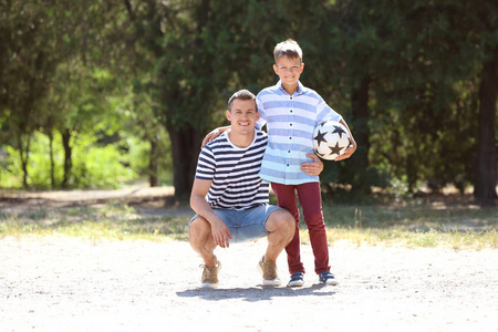 小男孩和他的爸爸在户外踢球