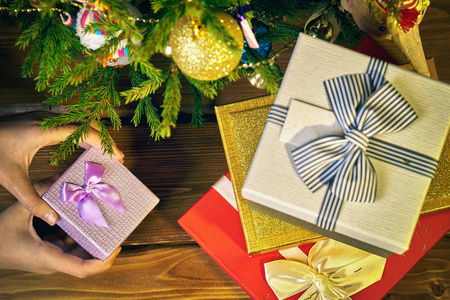 女孩的手打开或放在新的一年圣诞树下的一个小礼品盒
