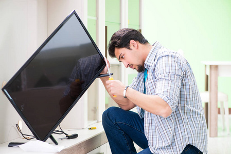 男青年丈夫在家修电视孤立的多彩复古修电视机.