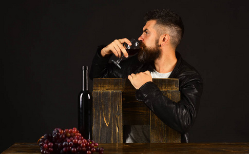 有胡子的男人在深褐色的背景下喝杯葡萄酒.degustator