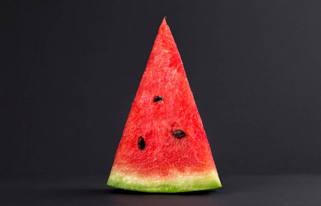 黑籽成熟西瓜三角片黑色背景特写镜头照片
