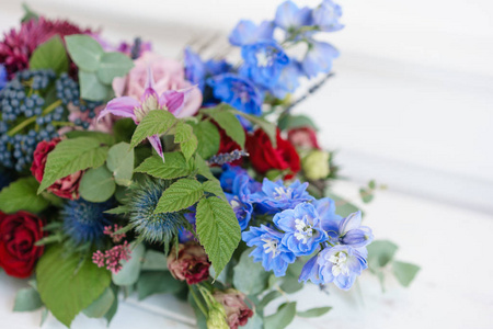 在老式金属花瓶中拉长的插花。表设置。蓝色和红色的颜色。华丽的花束, 不同的花朵。明亮的房间, 墙上的灰泥