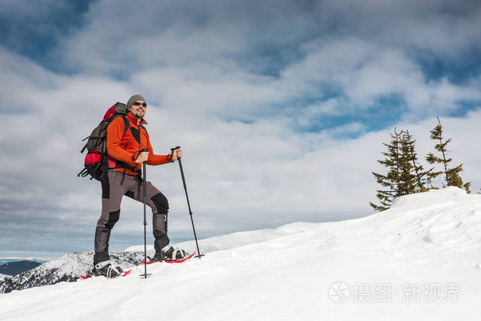 登山运动员在雪地鞋背着一个背包.在冬天的山上旅行.