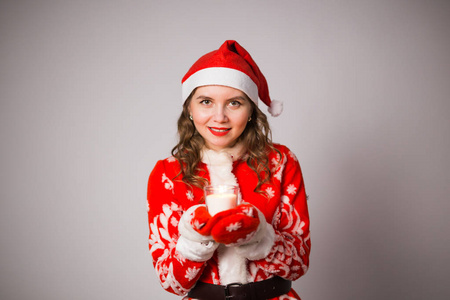 圣诞节, 庆祝, 人的概念一个穿着圣诞老人西装的女孩拿着蜡烛