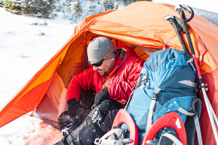 冬天在山里徒步旅行.橙色帐篷, 穿雪鞋和徒步竿.