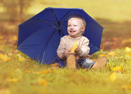 快乐的小孩坐在草地上与伞玩 y