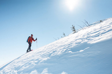 一个人爬上山顶.登山运动员在雪地鞋背着一个背包.在冬天的山上旅行.