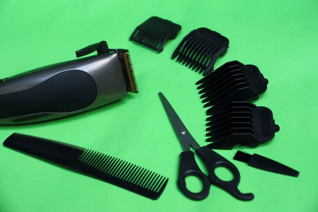 电动剪和一组配件从剪刀, 梳子和黑色附件的绿色表