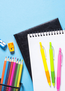 学校和办公用品或文具。在蓝顶视图上的笔记本记事本钢笔和铅笔