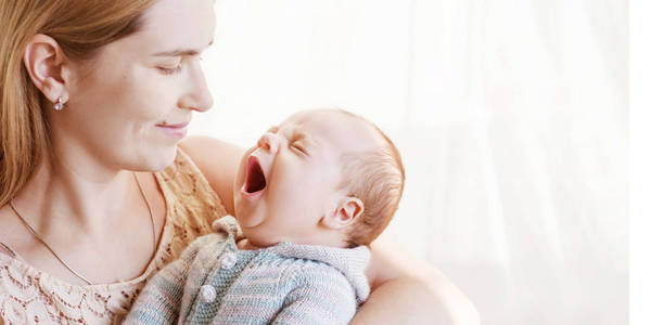 漂亮的女人抱着打呵欠的婴儿。使用复制空间关闭图像。母性观念。幸福家庭理念