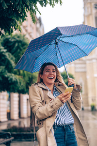 漂亮女人拿着雨伞在电话上发短信