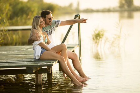 浪漫情侣坐在湖上的木码头上阳光明媚的日子