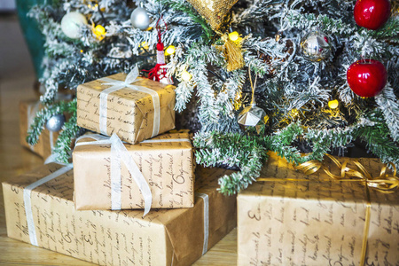 包装礼品的红色和白色的包装下的绿色圣诞树装饰圣诞玩具和蜡烛。背景是姜饼屋和黄色圣诞灯
