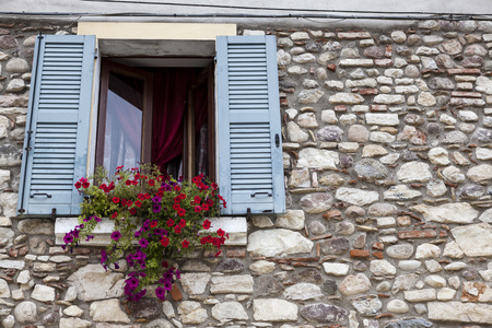 与旧窗口百叶窗打开石头墙上窗台上的花。意大利村