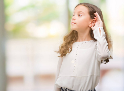 黑发西班牙裔女孩微笑着用手在耳朵听谣言或八卦.耳聋概念照片
