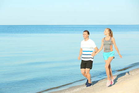 运动的年轻夫妇在海边奔跑