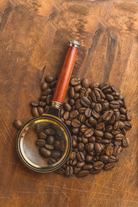 褐色咖啡豆中的圆形形状，特写的宏观背景和纹理的咖啡豆。对棕色木板与放大玻璃。Copyspace