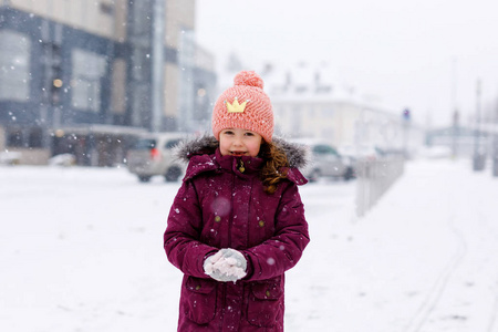 一个可爱的小女孩, 穿着五颜六色的衣服在雪里玩户外活动