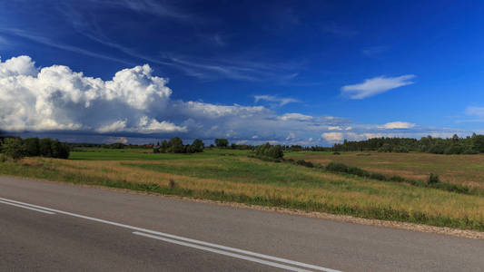 在白云和蓝天下, 绿草田野上的山路