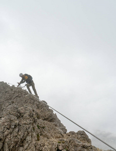 年轻有吸引力的男性登山者在陡峭和暴露通过 Ferrata 在南蒂罗尔巴迪亚在意大利白云岩